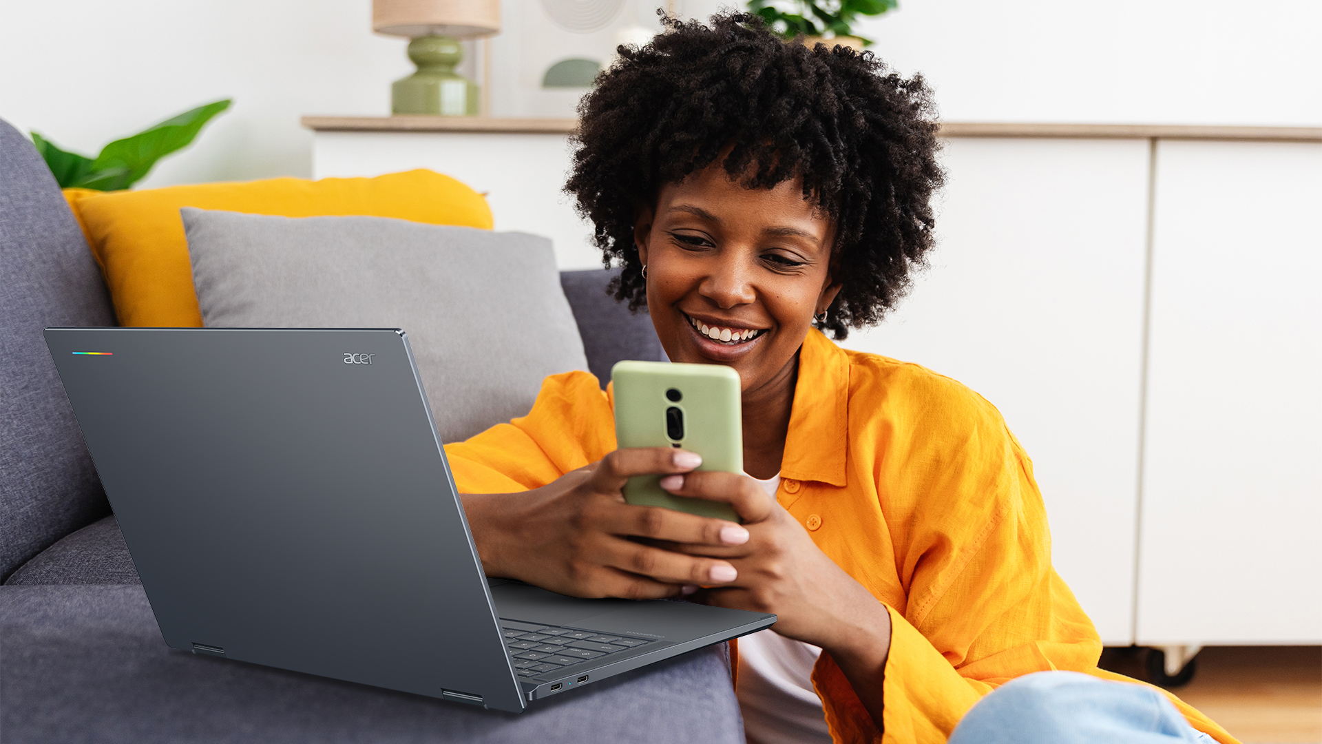A person uses a smartphone beside an open Acer Googlebook 14
